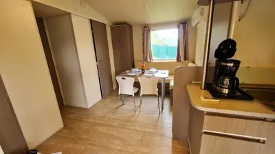 a kitchen with a table and chairs in a room at Mobil Home au calme Camping 4 Cadenet in Cadenet