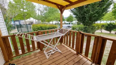 a white rocking chair sitting on a wooden deck at Mobil Home au calme Camping 4 Cadenet in Cadenet