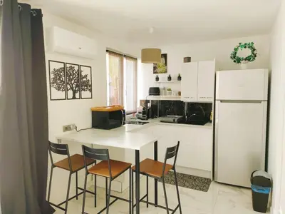 a kitchen with a table and chairs and a refrigerator at Appart 1 ch rénové avec piscine in Morières-lès-Avignon