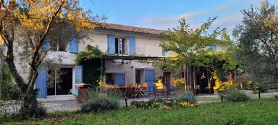 a fence in front of a house with purple wisterias at Location appartement dans mas provençal in Monteux