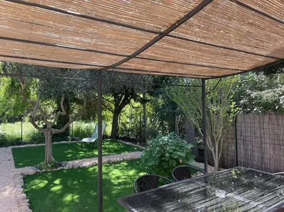 a picnic table under a wooden umbrella in a backyard at Mazet provençal in Eyguières