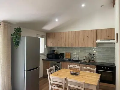 a kitchen with a table and a stainless steel refrigerator at Mazet provençal in Eyguières