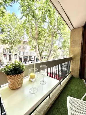 two wine glasses sitting on a table on a balcony at Studio Lumineux avec Terrasse in Aix-en-Provence