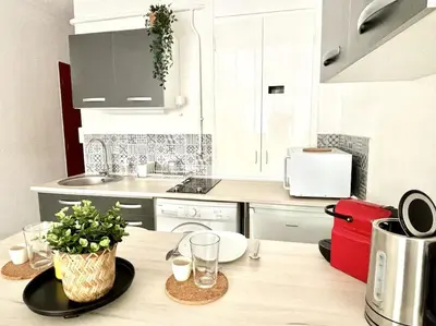 a kitchen with white cabinets and a wooden table at Studio Lumineux avec Terrasse in Aix-en-Provence