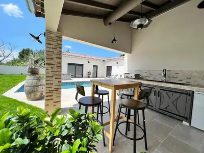 an outdoor kitchen with a table and bar stools at La Villa de Jéna in Mazan