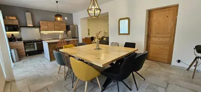 a kitchen and dining room with a wooden table and chairs at Mas Les Fabrys au coeur du Luberon in Bonnieux