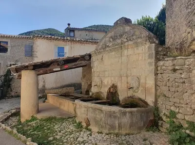 an old building with a fountain in front of it at La Castellane, vue imprenable sur le Luberon in Saignon