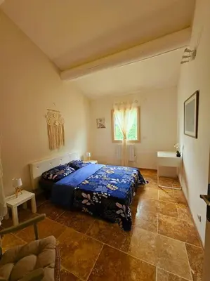 a bedroom with a blue bed and a window at La Castellane, vue imprenable sur le Luberon in Saignon
