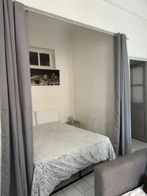a bedroom with a bed with curtains in it at Le Tanneur- Grand Studio 38m2 en centre-ville in Aix-en-Provence