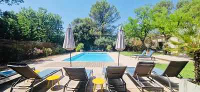 a patio with chairs and umbrellas next to a pool at La Maison du Soleil in Saint-Didier