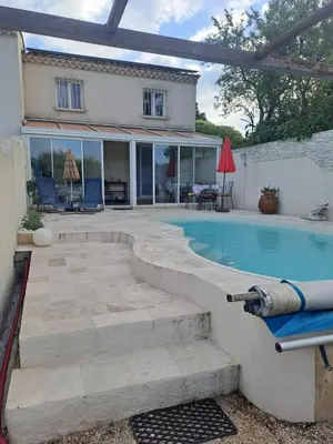 a swimming pool with a patio and a house at Jolie petite maison tout proche d avignon in Vedène