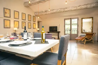 a dining room with a table with a bottle of wine on it at Domaine des Peyre in Robion en Luberon