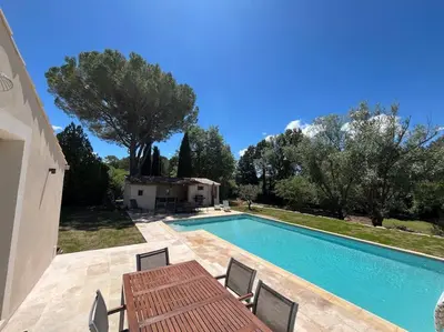 a swimming pool with a table and chairs next to a house at Havre de paix sur Roussillon in Roussillon