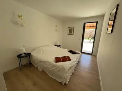 a white bedroom with a bed and a wooden floor at Havre de paix sur Roussillon in Roussillon