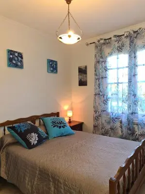 a bedroom with a bed with blue pillows and a window at La Villa St Antoine in LʼIsle-sur-la-Sorgue
