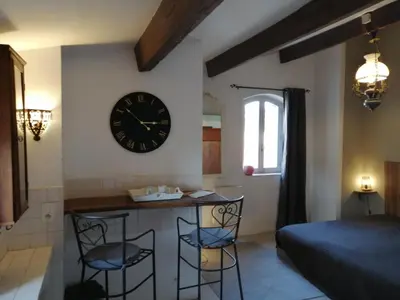 a room with a clock on the wall and two bar stools at Le Perchoir in Mérindol