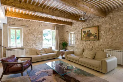 a living room with two couches and a stone wall at Mas authentique à Eygalières in Eygalières