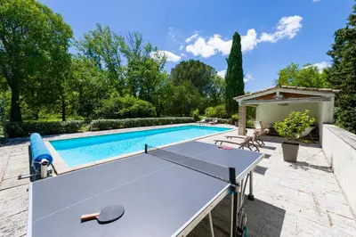 a ping pong table in front of a swimming pool at Mas authentique à Eygalières in Eygalières