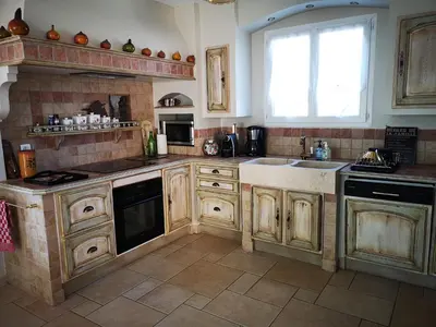 a kitchen with wooden cabinets and a sink and a window at La Colline, villa avec piscine in Châteaurenard
