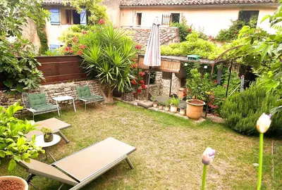 a garden with a table and an umbrella and plants at La Cigalou - Bonnieux Centre in Bonnieux