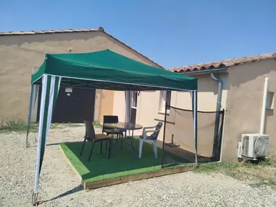 a tent with chairs and a table in front of a house at Au Petit Luberon in Cheval-Blanc