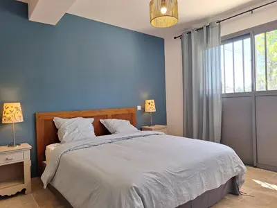 a blue bedroom with a bed and a window at Mas Les Figuières in Monteux