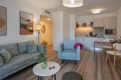 a living room with a blue couch and a kitchen at DOMITYS - L'Amandier in Aix-en-Provence