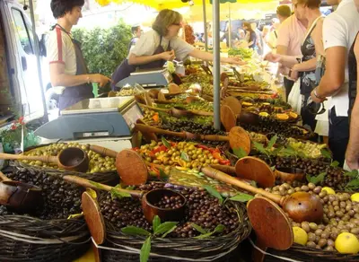 a group of people standing around a display of fruits and vegetables at Logement studio avec vue sur le centre Historique in LʼIsle-sur-la-Sorgue