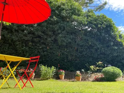 a red umbrella and a red chair in a yard at Bastide de la Couloubre in Mallemort