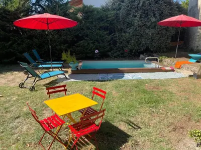 a table and chairs with umbrellas next to a pool at Bastide de la Couloubre in Mallemort