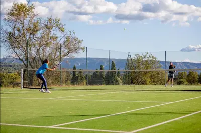 two people playing tennis on a tennis court at Gîte Confortable Vue Exceptionnelle - Golf de Saumane in Saumane-de-Vaucluse