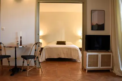 a bedroom with a bed and a tv and a table at Gîte Confortable Vue Exceptionnelle - Golf de Saumane in Saumane-de-Vaucluse