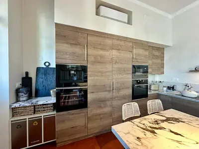 a kitchen with wooden cabinets and a table and chairs at Divine Idylle Luxe 3 chambres, terrasse 130m2, jacuzzi, Clim 5 m Cours Mirabeau in Aix-en-Provence