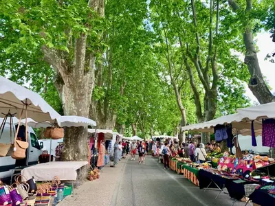 a group of people walking through a market with tables at Maison de charme provençale en pierre in Puyvert
