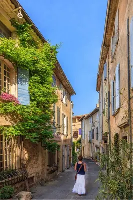 a woman walking down a street in an alley at Maison de charme provençale en pierre in Puyvert