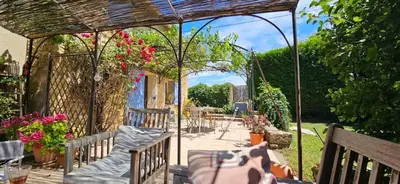 a pergola with chairs and flowers on a patio at Maison de charme provençale en pierre in Puyvert