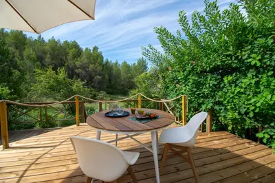 a wooden deck with a table and chairs and an umbrella at Juste en Provence in Saint-Saturnin-les-Apt