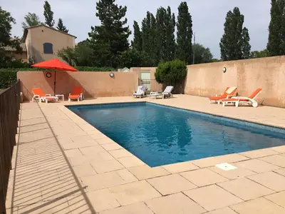 a swimming pool with chairs and an umbrella at les couleurs du sud in Aix-en-Provence