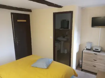 a bedroom with a yellow bed and a sink at Chambres d'hôtes L'Amphitryon 5 CHAMBRES in Villemus