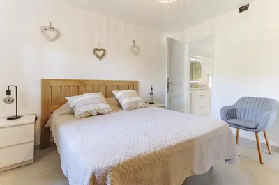 a white bedroom with a bed and a blue chair at Le Petit Nid in Saint-Rémy-de-Provence
