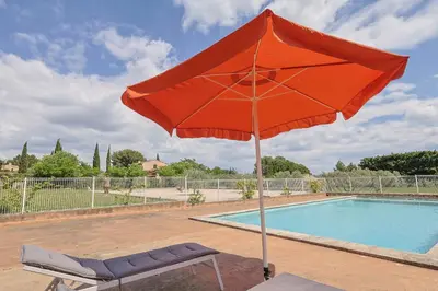 a red umbrella and a chair next to a pool at Le Petit Nid in Saint-Rémy-de-Provence