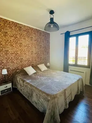 a bedroom with a large bed with a brick wall at L'Apt Tropez in Apt