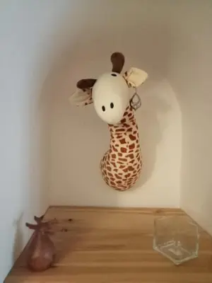 a stuffed giraffe hanging on a wall at petite maison avec jardin calme in Le Thor