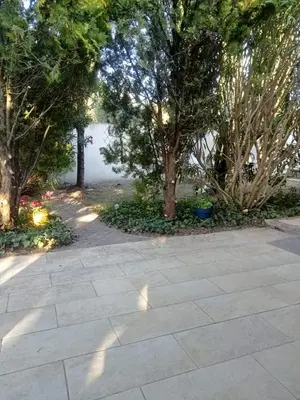 a stone walkway with trees in a park at petite maison avec jardin calme in Le Thor