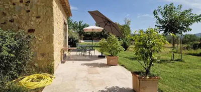 a patio with trees and an umbrella in a yard at La Bastide des Muriers in Gargas
