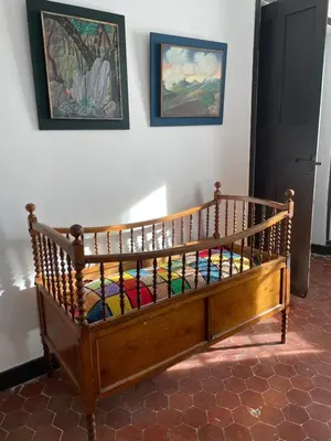 a wooden crib in a room with paintings on the wall at La Maison Joly in Ménerbes