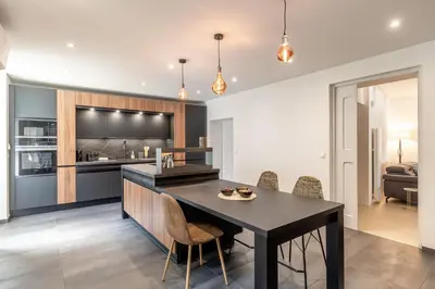 a kitchen with a black island with chairs and a table at Oasis de Gordes in Gordes