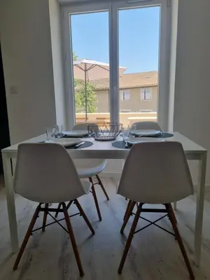 a white dining room table with two chairs and a window at Maison de village avec terrasse in Grans