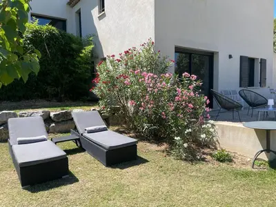 a patio with two chairs and a table and flowers at Le jardin de Vaumartin in Meyrargues