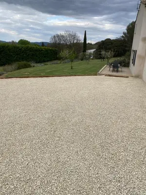 a gravel driveway next to a building with a bench at Le jardin de Vaumartin in Meyrargues
